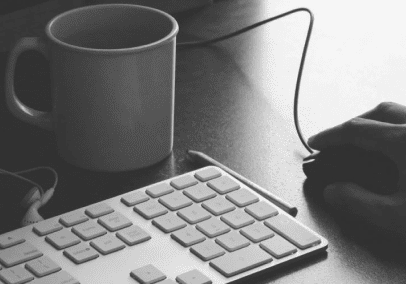 Hand using computer mouse and keyboard.