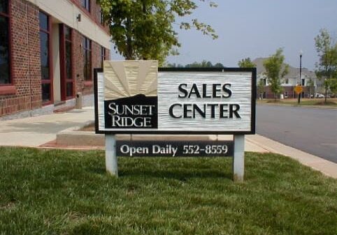 Sales center sign outside brick building.