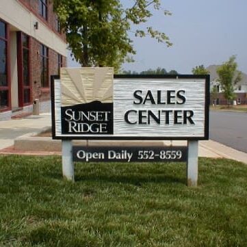 Sales center sign outside brick building.